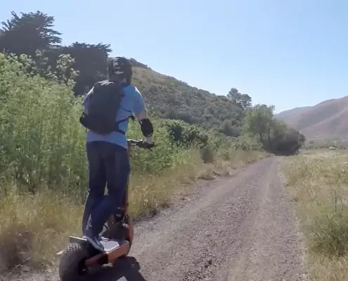 Man with backpack riding an off road electric scooter